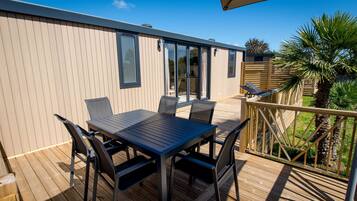 A deck with a table and chairs, a wooden fence, and a palm tree.