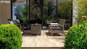 A modern outdoor seating area with wicker furniture, a glass table, and lush greenery. - CITY HOUSE SA FONT IN SANTA CATALINA (Palma)