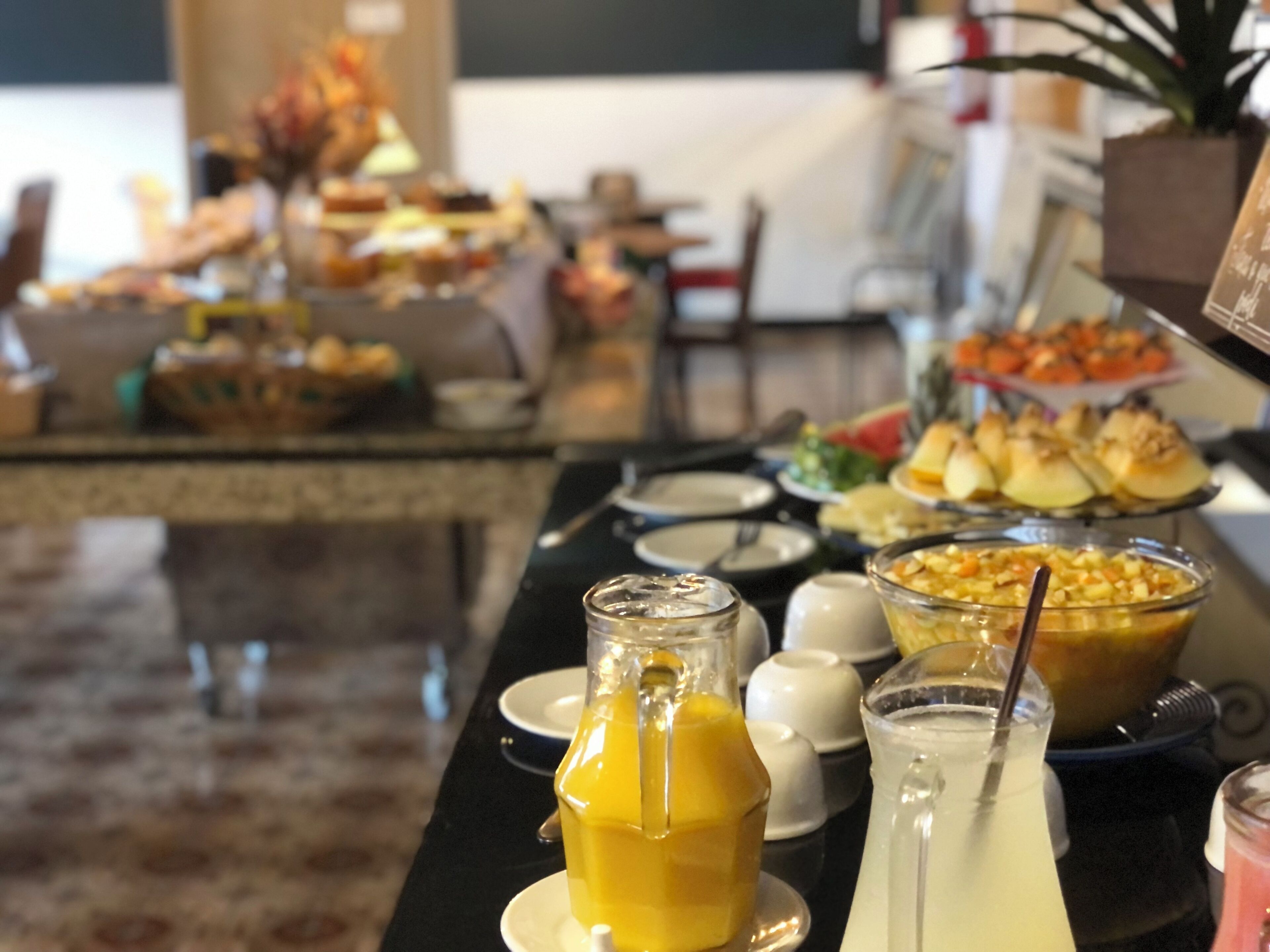 Ein reichhaltiges Buffet mit verschiedenen Speisen und Getränken, darunter ein Glas Orangensaft und eine Kanne eines weißen Getränks.