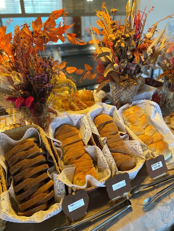 Una vitrina de panadería con diferentes tipos de pan y arreglos florales decorativos.