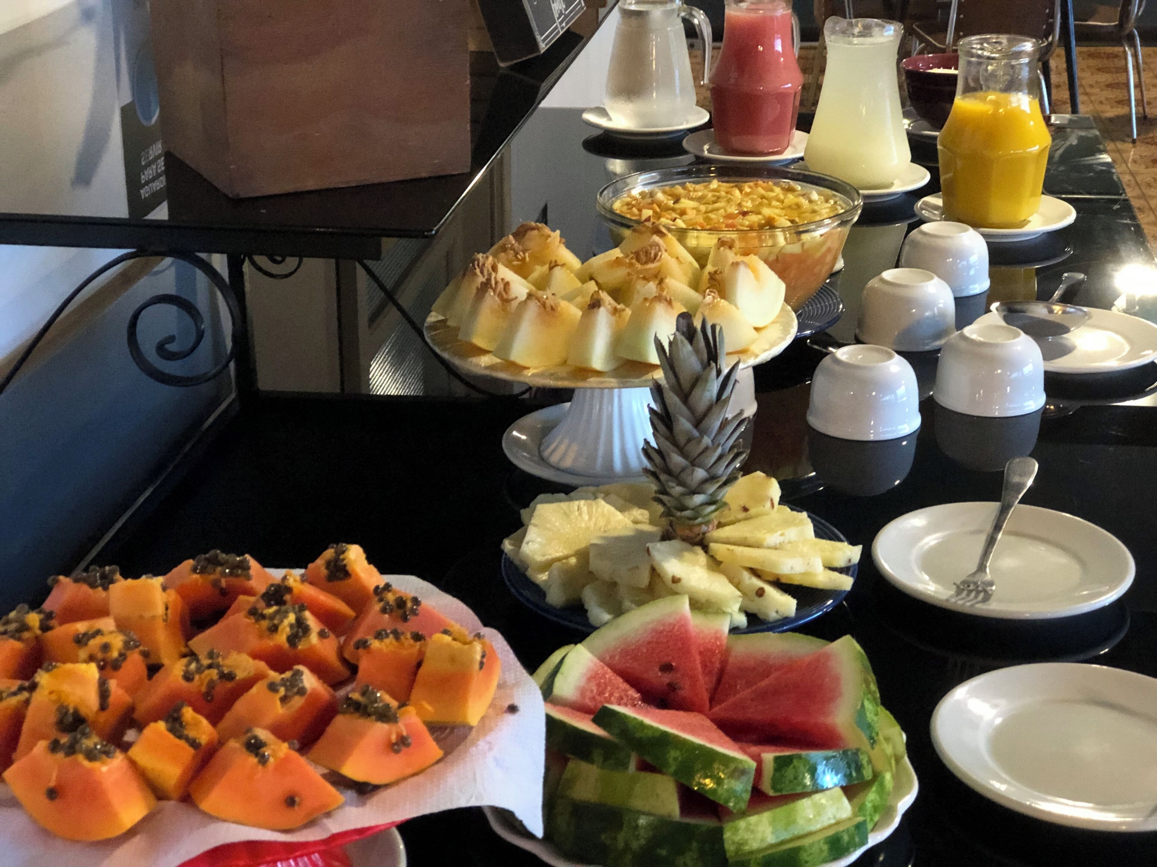 Un bufé de desayuno con diversas frutas, una piña y un tazón de granola.