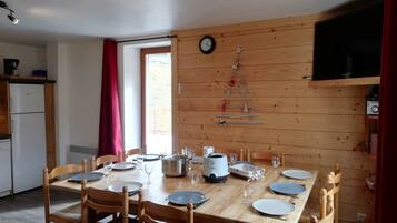 Une table de salle à manger en bois, mise avec des assiettes, des verres et une bouilloire.