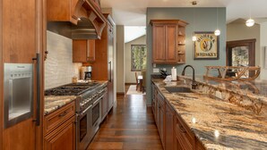 A spacious kitchen with wooden cabinets, a granite countertop, and a built-in stove. - Short Walk to River Run, Private Hot Tub, Tons of Sunshine and Natural Light (Keystone)