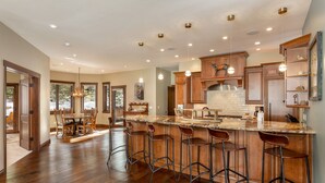 A spacious kitchen with a large island, wooden bar stools, and pendant lighting. - Short Walk to River Run, Private Hot Tub, Tons of Sunshine and Natural Light (Keystone)