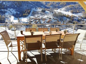 Un comedor con mesa y sillas, con vistas a un pueblo montañoso cubierto de nieve.