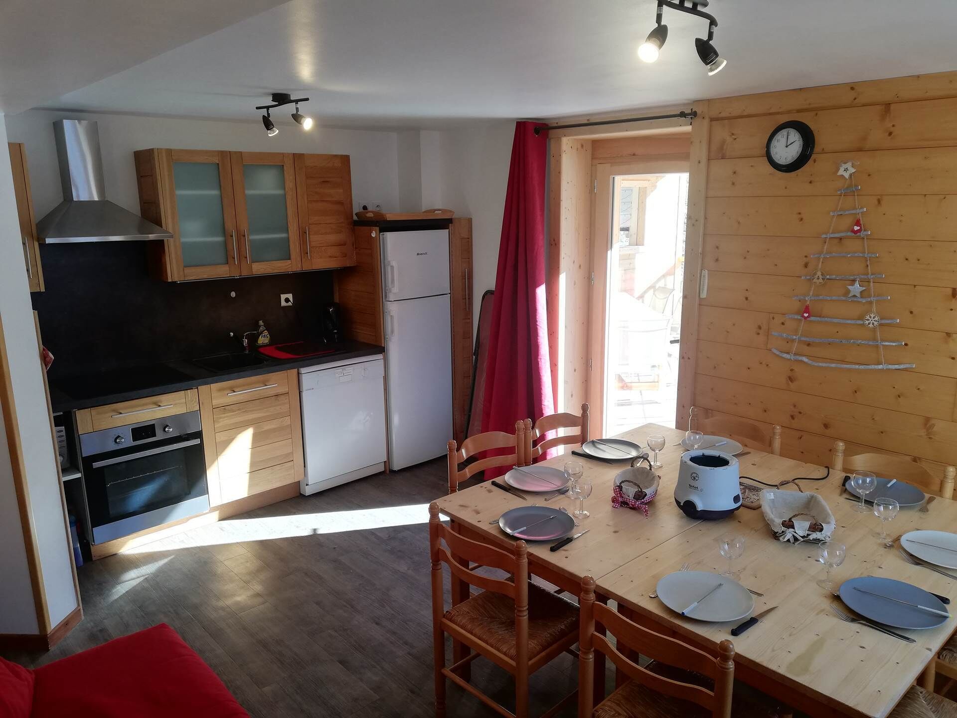 A compact kitchen with wooden cabinets, a refrigerator, and a dining area with a table set for four.
