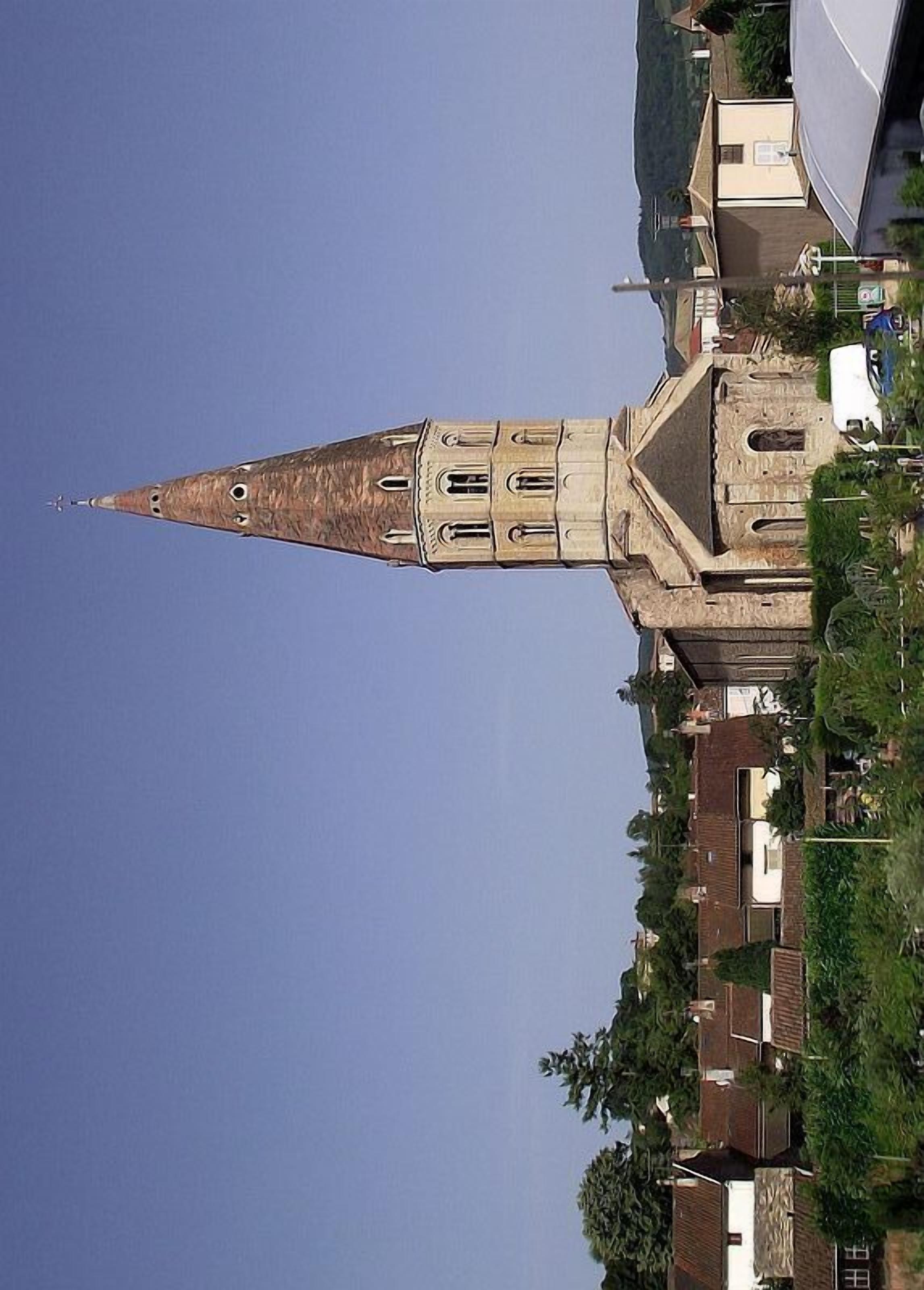Une église dotée d’un clocher imposant et de nombreuses fenêtres, entourée d’immeubles résidentiels et de verdure.