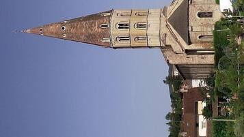 Une église dotée d’un clocher imposant et de nombreuses fenêtres, entourée d’immeubles résidentiels et de verdure.