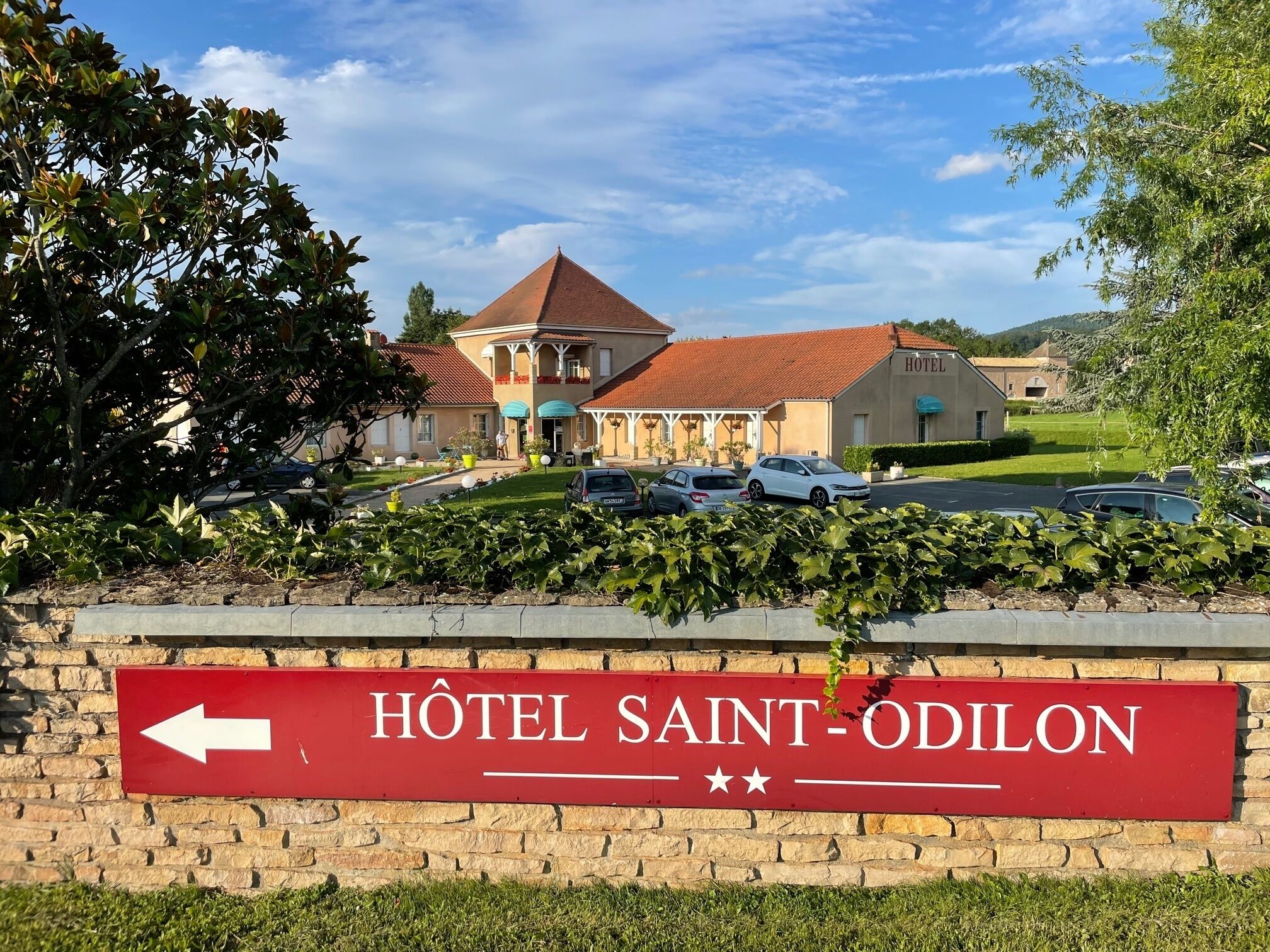 Une enseigne d’hôtel avec une flèche pointant vers la gauche, indiquant la direction de l’hôtel SAINT-ODILON.