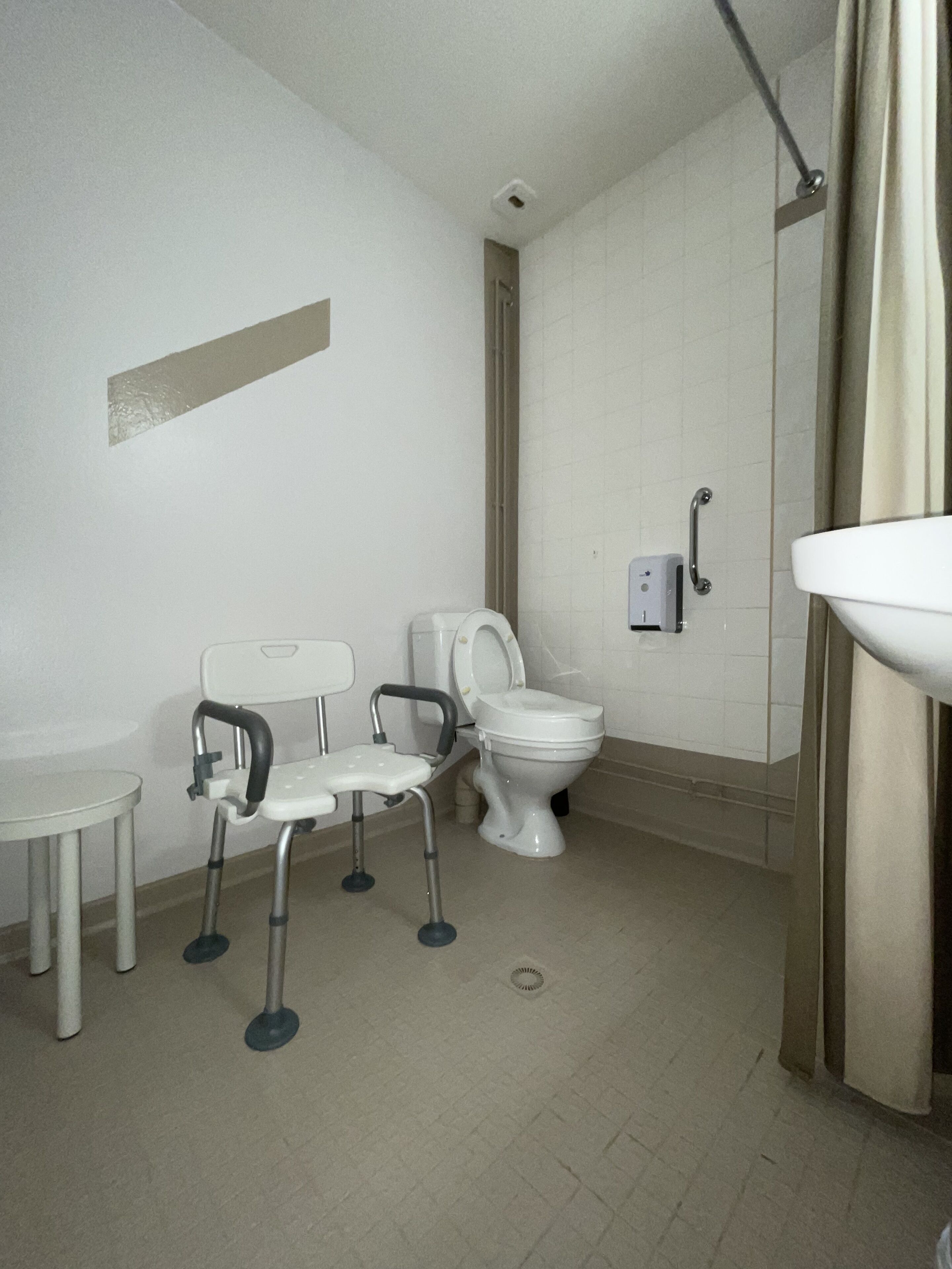 Un bagno piccolo e pulito, con il water, un lavandino e una sedia.