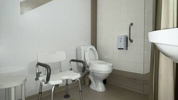 A small, clean bathroom with a toilet, a sink, and a chair.