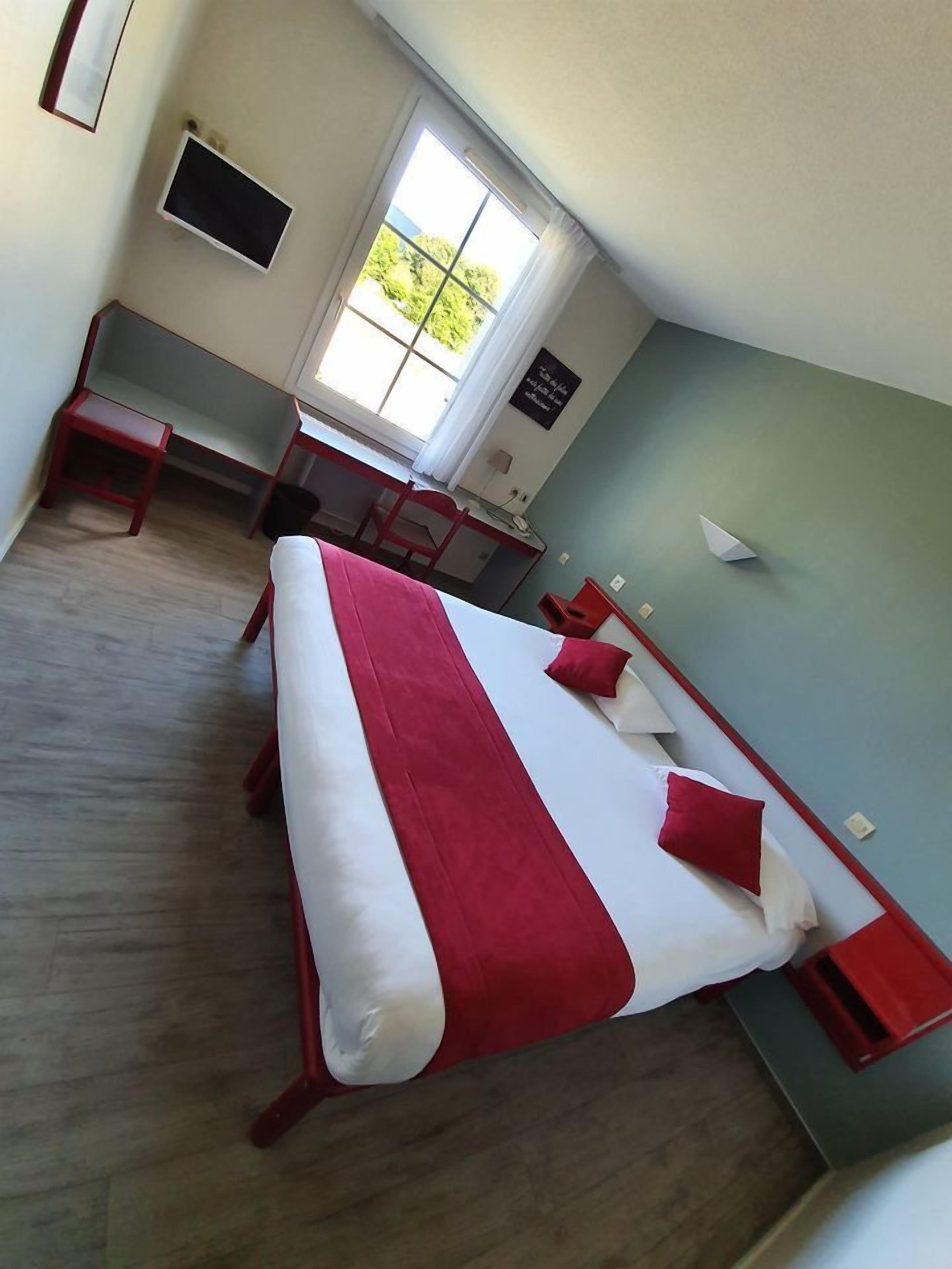 Habitación de hotel con una cama grande, un escritorio, una silla, un televisor y una ventana.