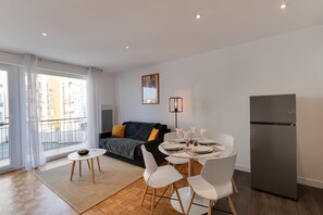 En modern lägenhet med ett matområde, en soffa och ett kylskåp.