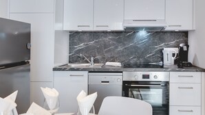 A modern kitchen with white cabinetry, a marble backsplash, and a dining area set for a meal. - 🎖 Le Chevène - 2 or 4 person apartment with balcony in Annecy Centre (Annecy)