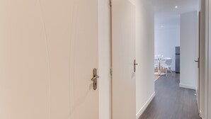 A hallway with a closed door, a dining area with a table and chairs, and a kitchen in the background. - 🎖 Le Chevène - 2 or 4 person apartment with balcony in Annecy Centre (Annecy)