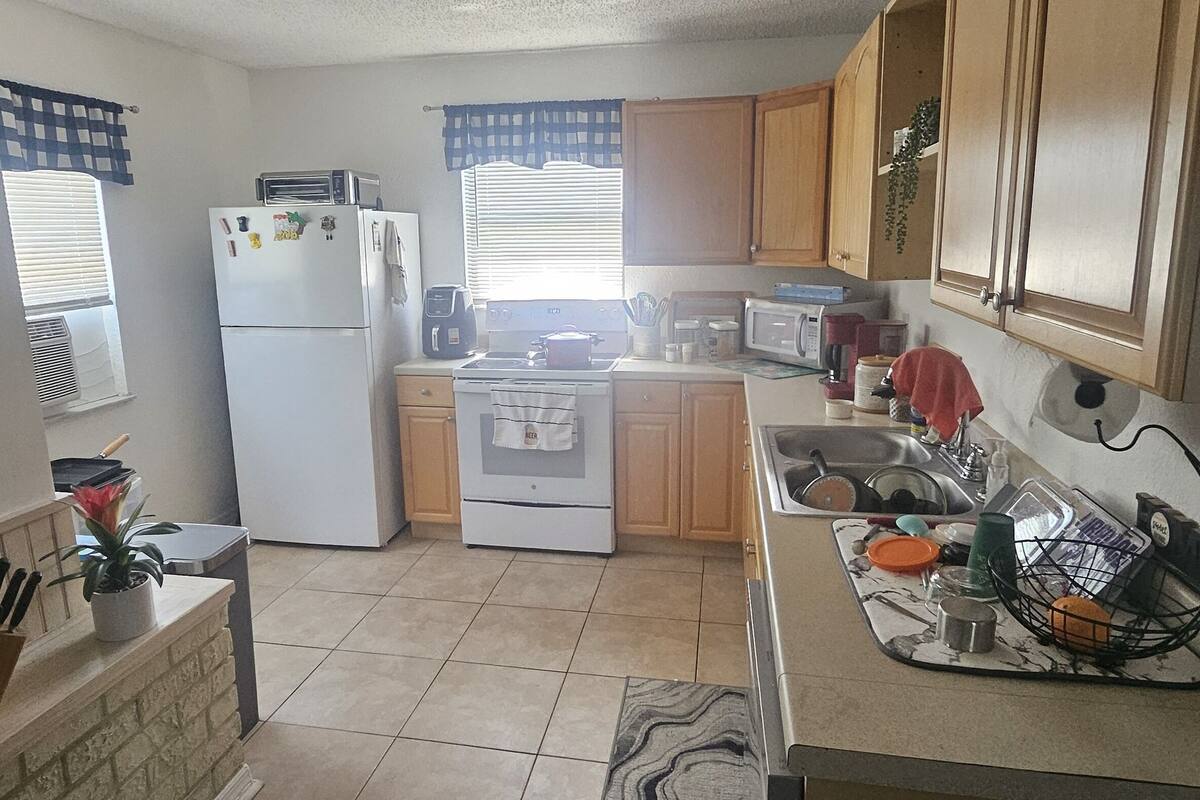 A compact kitchen with a refrigerator, stove, microwave, and sink.