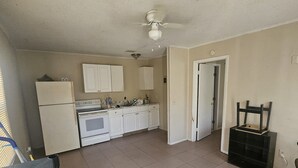 A kitchen with white cabinets, a stove, and a ceiling fan. - Sebastian Gardens Inn & Suites (Sebastian)