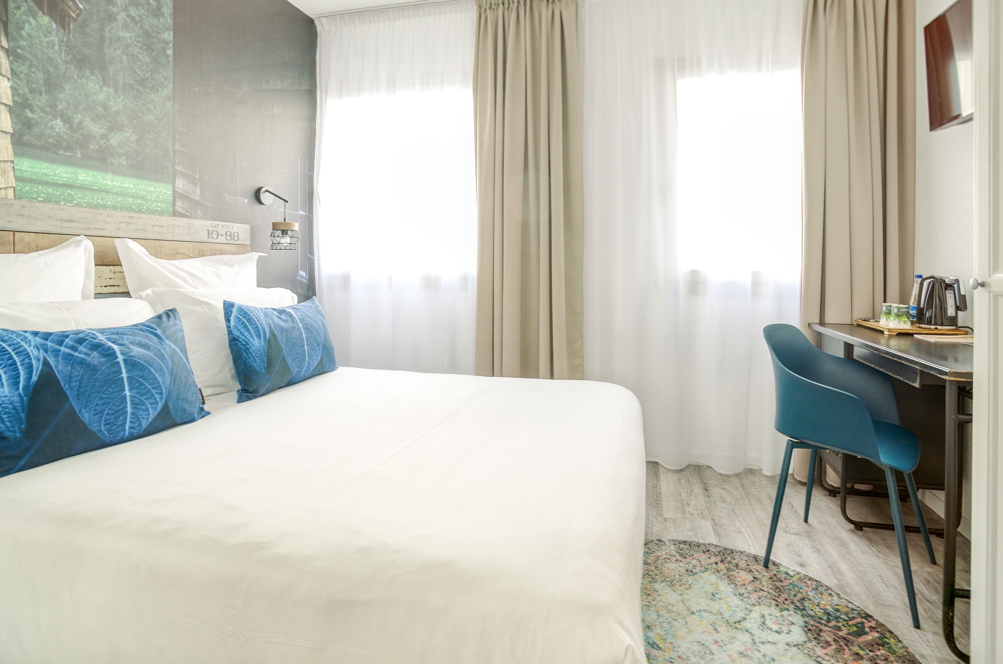 Una habitación de hotel con una cama, un escritorio y una silla.
