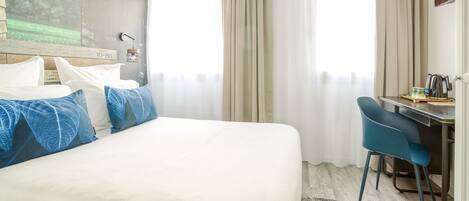 Una habitación de hotel con una cama, un escritorio y una silla.