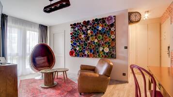 A modern living room with a round leather chair, a wooden coffee table, and a vibrant wall art piece made of colorful circular objects.