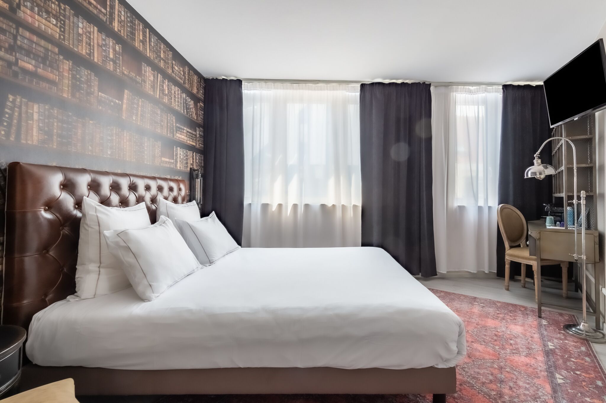 A hotel room with a large bed, a desk, and a chair.