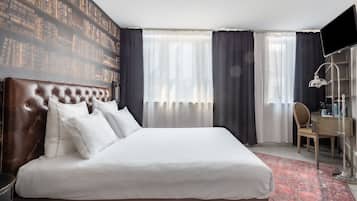 A hotel room with a large bed, a desk, and a chair.