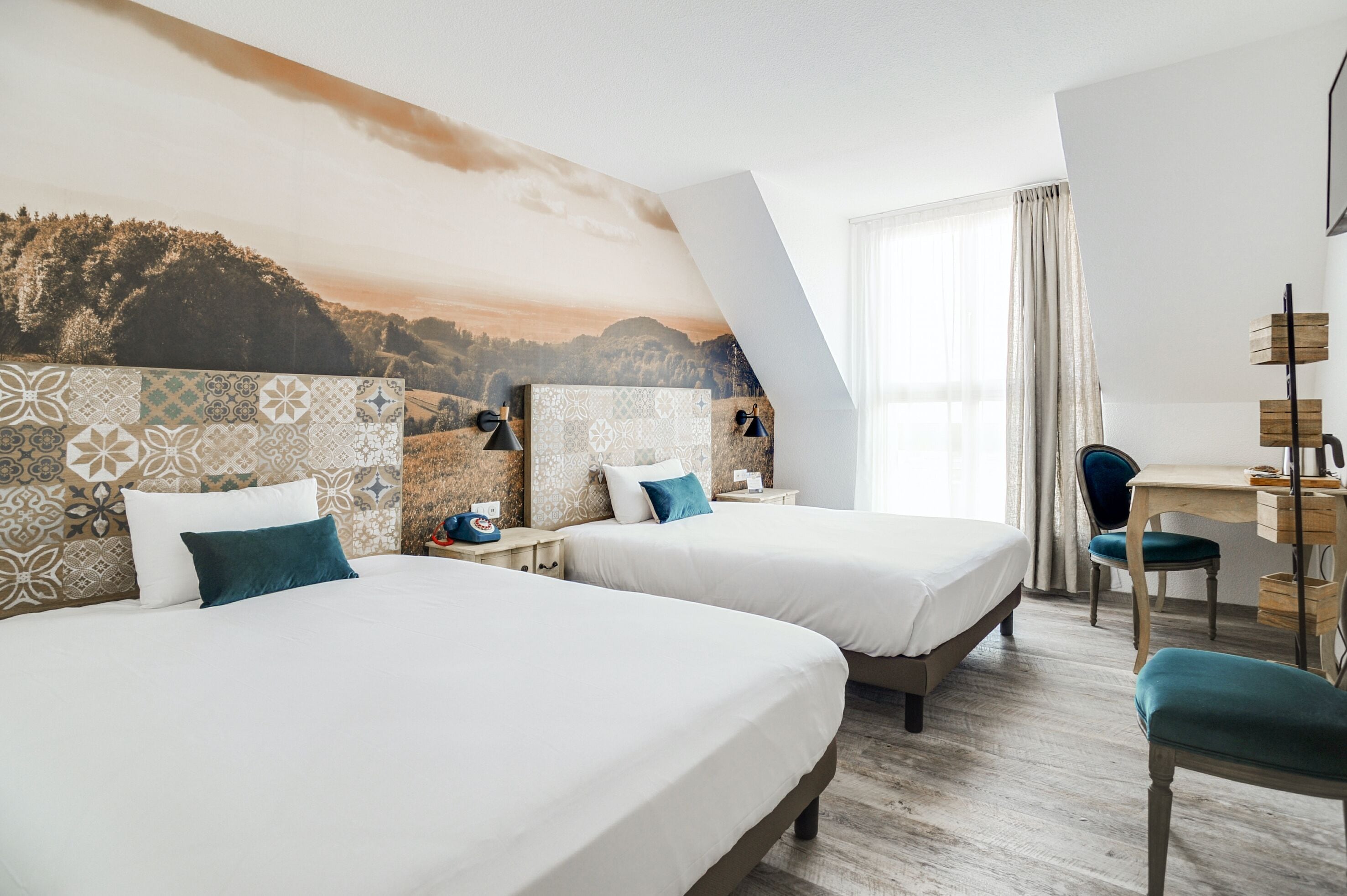 A hotel room with two beds, a desk, and a chair.