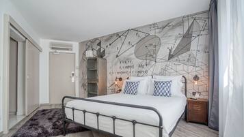 A bedroom with a bed, a nightstand, a wall-mounted air conditioner, a door, and a patterned rug.