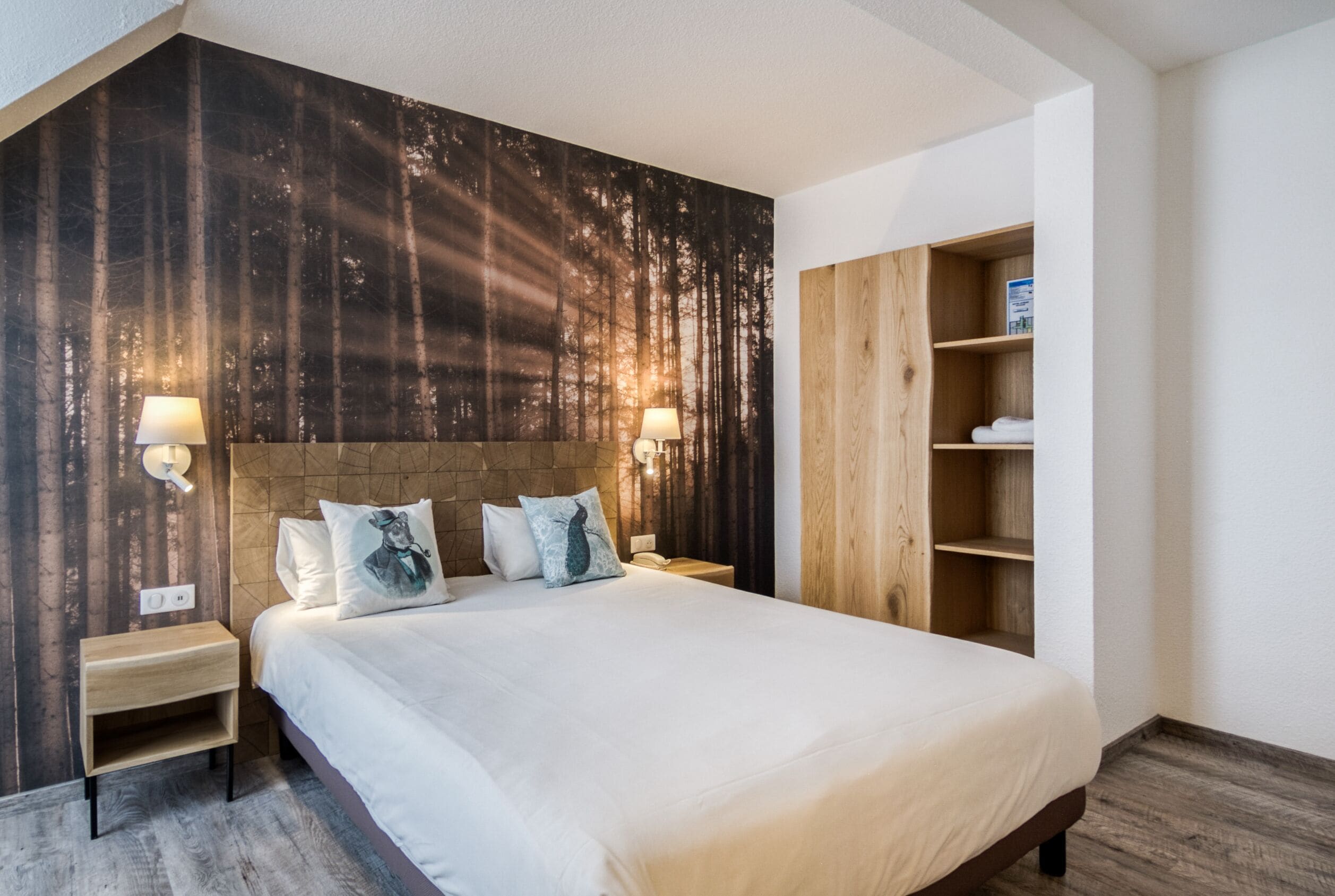 Un dormitorio moderno con una cama grande, cabecera de madera, dos mesitas de noche con lámparas y una estantería de madera empotrada.