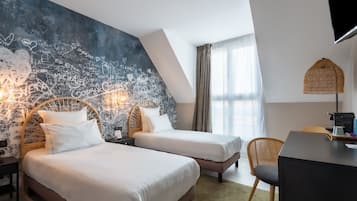 A hotel room with two beds, a large chalkboard wall with writings, a desk with a chair, and a TV mounted on the wall.