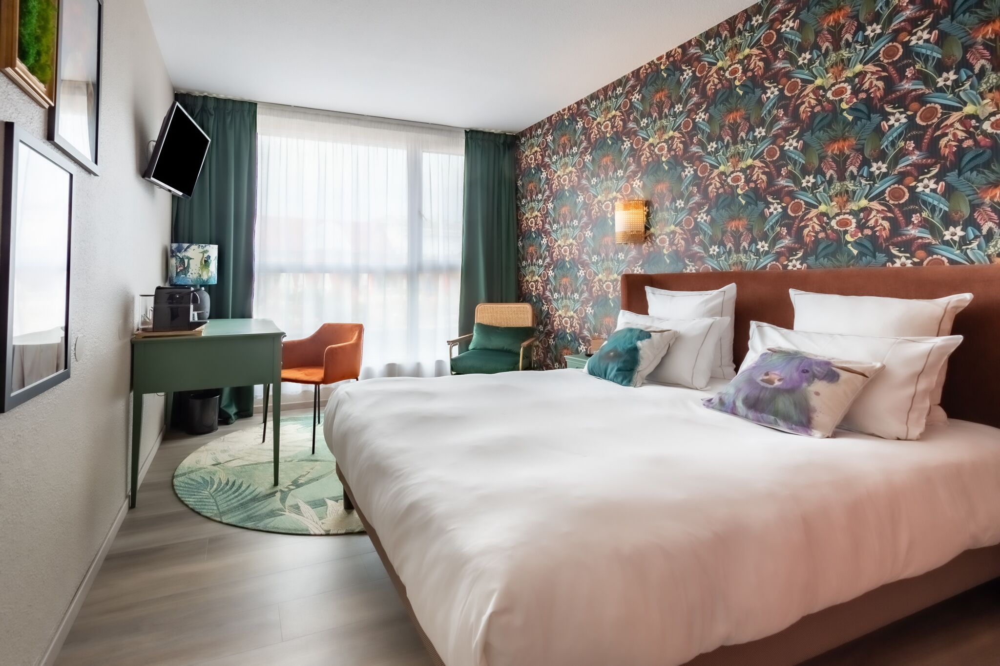 A hotel room with a bed, a desk, a chair, a television, and a window with curtains.