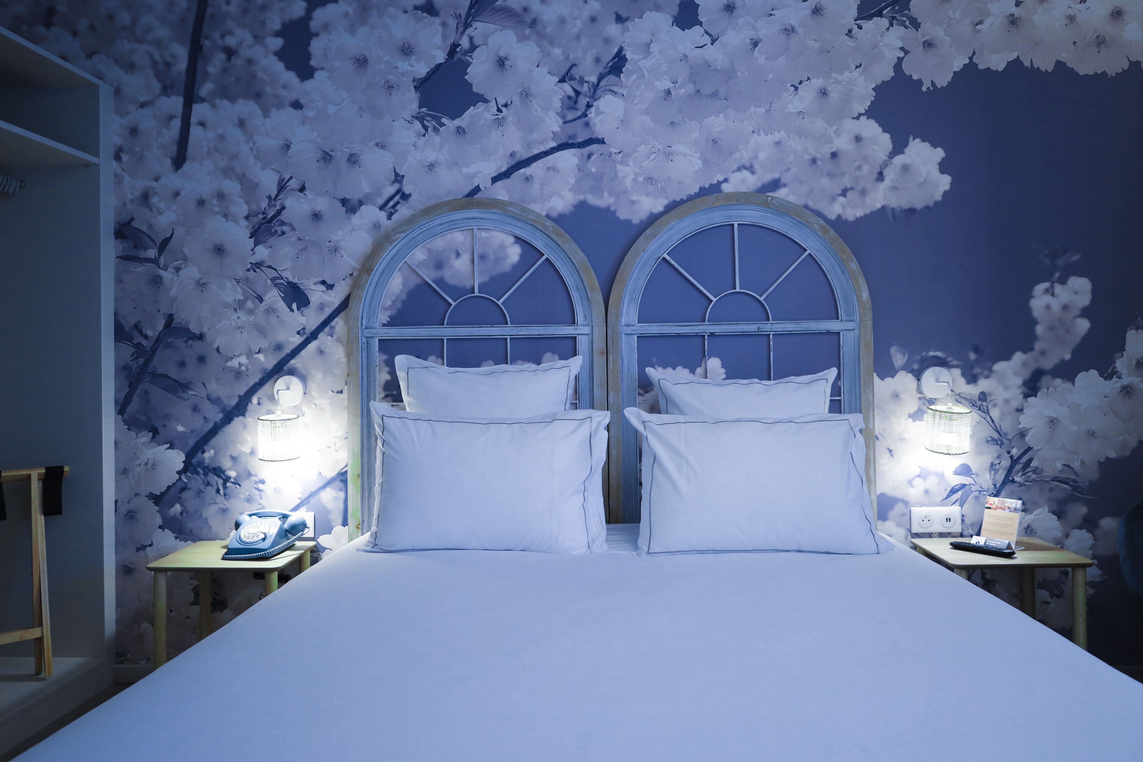 A bedroom with a large bed, two nightstands, and a wall with cherry blossom wallpaper.