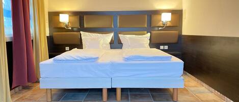 A double bed with white linens, two bedside tables with lamps, and a headboard with a light panel.