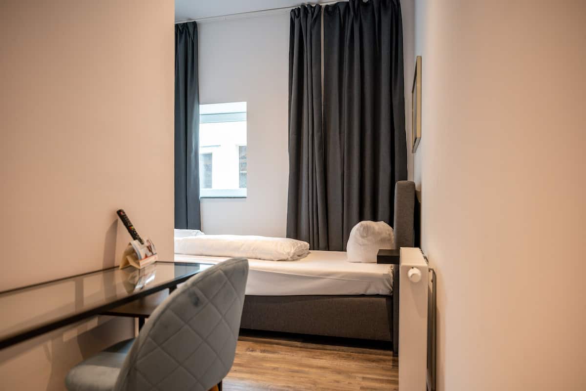 A compact hotel room with a bed, a desk, and a chair.