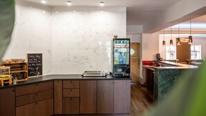 A modern kitchen with a marble backsplash, wooden cabinets, a built-in refrigerator, and a chalkboard with a motivational quote. - Hotel Vintage (Pulheim)