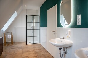 Bathroom features a glass shower enclosure, white sink, and towel rack.