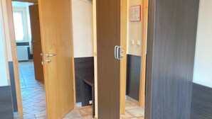 A hallway with a tiled floor, wooden doors, and a view into another room. - Hotel Vintage (Pulheim)