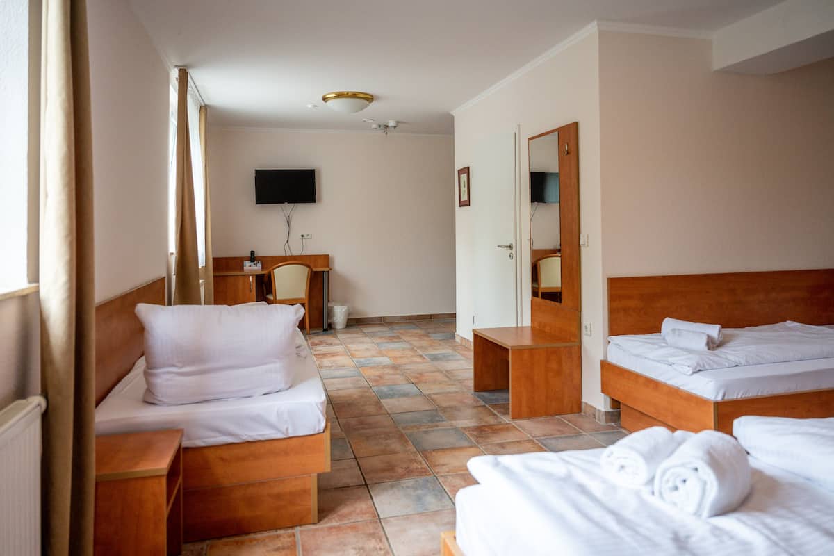 A hotel room with two beds, a desk, a chair, a television, and a bathroom door.