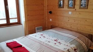 A wooden-paneled room with a bed, a window, and three framed pictures on the wall. - Gîte 1- 8 persons- 4 bedrooms- Covered terrace (VALMEINIER)
