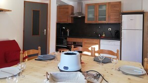 A compact kitchen with wooden cabinets, a black countertop, and a white refrigerator. - Gîte 1- 8 persons- 4 bedrooms- Covered terrace (VALMEINIER)