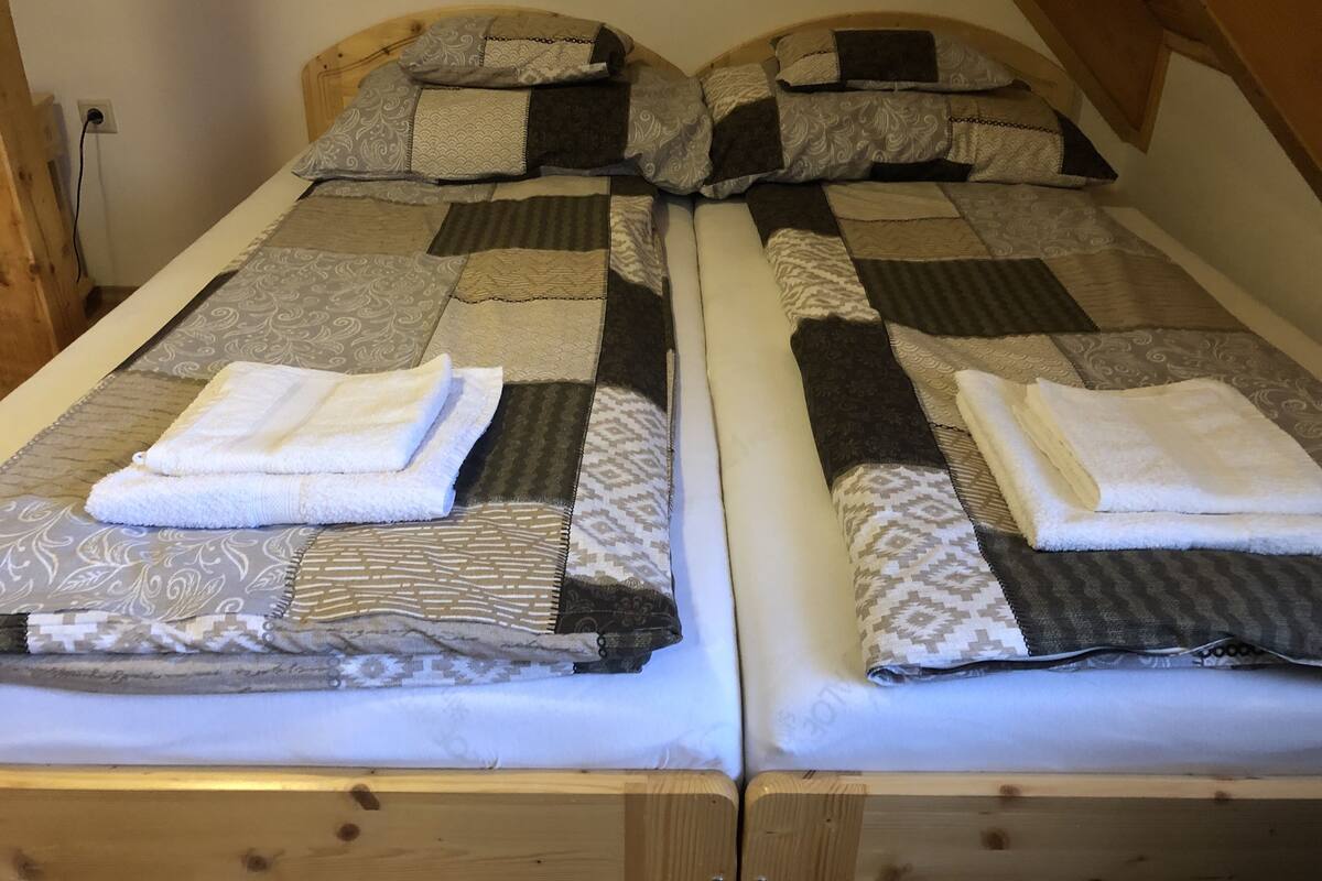 Two single beds with wooden frames and headboards, each with a quilted bedspread and two pillows.