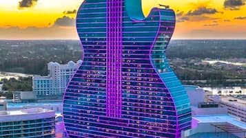 A building shaped like a guitar with a pool and a view of the city.
