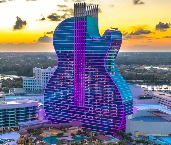 A building shaped like a guitar with a pool and a view of the city.