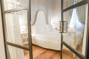 Un dormitorio con una cama grande, una mesita de noche con una lámpara y un espejo que refleja la habitación.