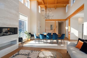Amplia sala de estar con chimenea, mesa de comedor y sillas azules.