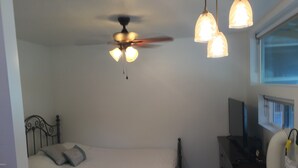 A bedroom with a bed, a ceiling fan, a heater, and a window.