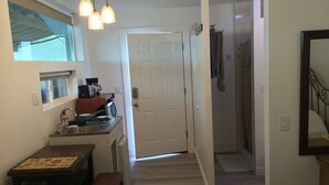 A compact kitchen with a dining area, a white door, and a hallway leading to a bathroom.