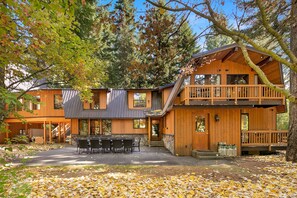 Enjoy a forest view from the upper-level balcony of this two-story cabin, featuring a covered patio with a dining area.