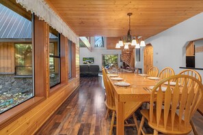 Enjoy a casual meal at this rustic cabin-style dining area with a long wooden table and pendant lights.
