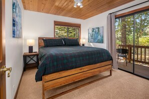 Relax in this serene bedroom with a comfortable bed, two nightstands, and a window offering a view of the surrounding trees.